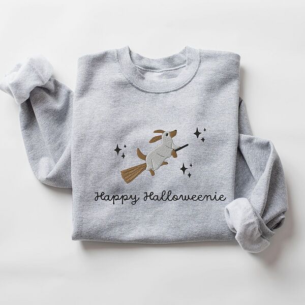 Sport Grey crewneck sweatshirt laid flat on white, embroidered with a ghost dachshund riding a broom among black stars above the words Happy Halloweenie