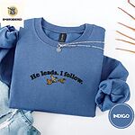 Indigo Blue crewneck sweatshirt folded with light jeans and dried twigs, embroidered with three mallard ducks flying under the arched words He leads. I follow. in black thread