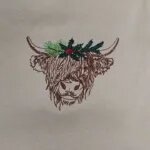Close-up video of the embroidered highland cow with a holly and pine crown on a Sand sweatshirt