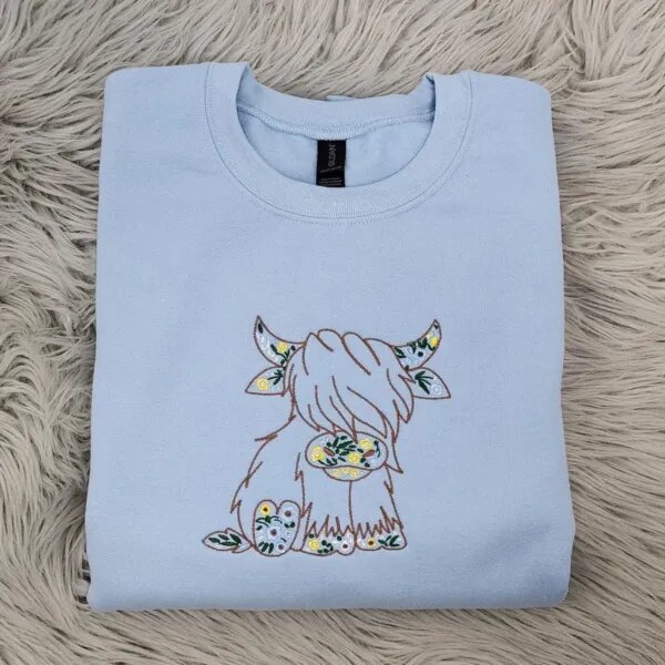 Light Blue Highland cow crewneck with the embroidered floral Highland cow centered on the chest