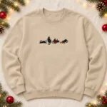 Sand holiday cat sweatshirt with four embroidered black cats, a Santa hat, Christmas lights, a gift box and ornaments across the chest