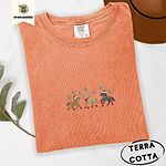 Terracotta Comfort Colors T-shirt embroidered with three horses in Santa hats, a red scarf and red leg wraps trotting under turquoise snowflakes