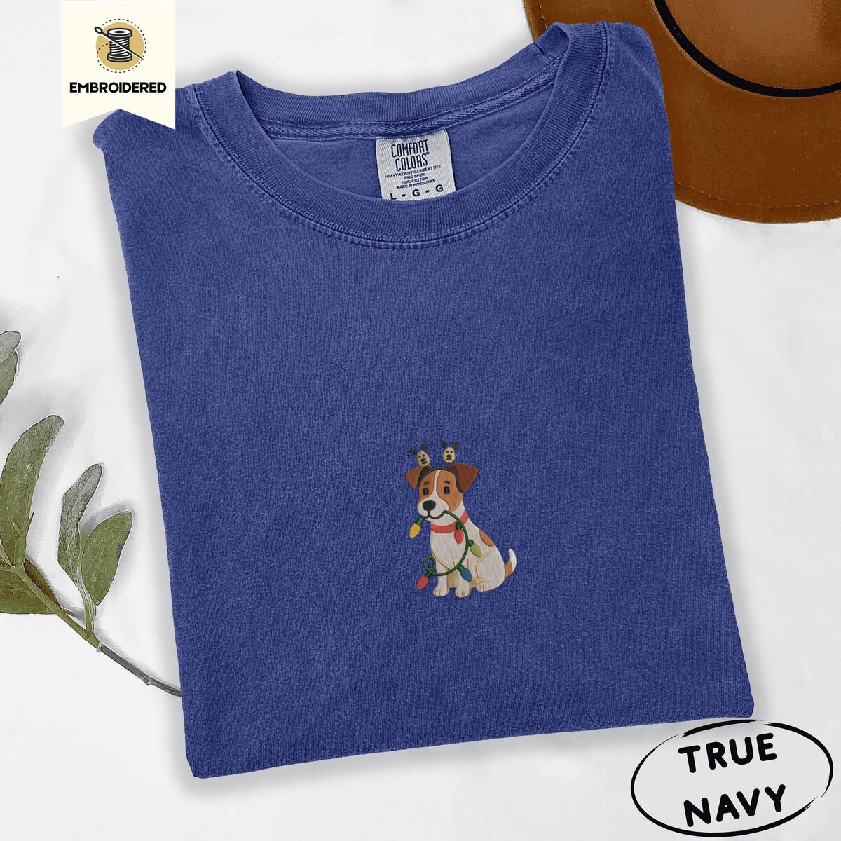 Jack Russell Christmas Lights Shirt – True Navy True Navy Comfort Colors T-shirt embroidered with a white and tan Jack Russell puppy in a reindeer headband chewing a string of Christmas lights