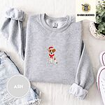 Ash Jack Russell Christmas sweatshirt folded with denim shorts, white sneakers and a potted plant, with a mini embroidered Jack Russell puppy in a Santa hat and red scarf centered on the chest