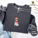 Dark Heather Jack Russell Christmas sweatshirt folded with ripped jeans and a silver chain necklace, with a mini embroidered Jack Russell puppy in a Santa hat and red scarf centered on the chest