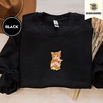 Black crewneck sweatshirt with a brown felt hat and dried bunny tail grass, embroidered with two fluffy orange tabby kittens, one winking with a paw on the other's head