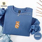 Indigo Blue crewneck sweatshirt folded with light jeans and dried twigs, embroidered with two fluffy orange tabby kittens, one winking with a paw on the other's head