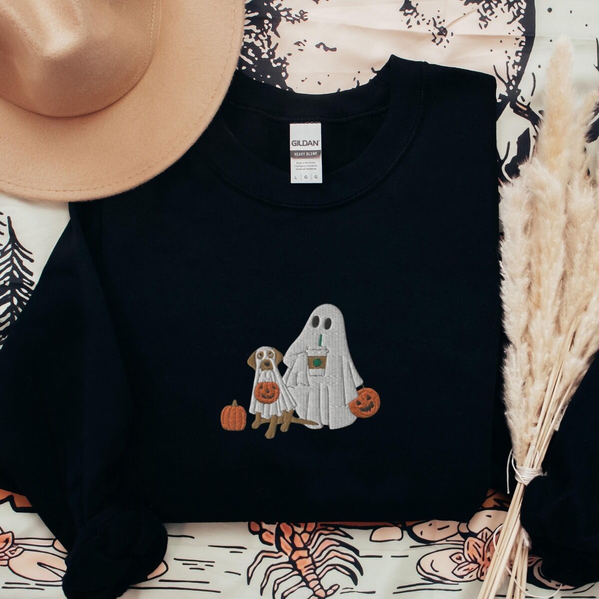 Lab Mom Ghost Sweatshirt – Black Black crewneck sweatshirt laid flat with a brown hat and pampas grass, embroidered with a ghost lab mom holding a coffee cup and a jack-o'-lantern pail beside a tan lab in a ghost sheet with its own pumpkin pail