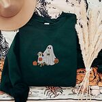 Forest Green crewneck sweatshirt laid flat with a brown hat and pampas grass, embroidered with a ghost lab mom holding a coffee cup and a jack-o'-lantern pail beside a tan lab in a ghost sheet with its own pumpkin pail