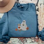 Indigo Blue crewneck sweatshirt laid flat with a brown hat and pampas grass, embroidered with a ghost lab mom holding a coffee cup and a jack-o'-lantern pail beside a tan lab in a ghost sheet with its own pumpkin pail