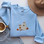 Light Blue crewneck sweatshirt laid flat beside jeans and a coffee cup, embroidered with a ghost lab mom holding a coffee cup and a jack-o'-lantern pail beside a tan lab in a ghost sheet with its own pumpkin pail