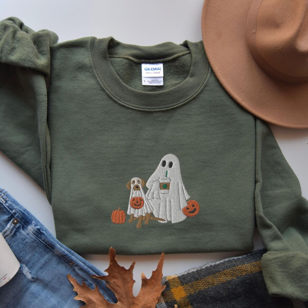 Lab Mom Ghost Sweatshirt – Military Green Military Green crewneck sweatshirt laid flat beside jeans, a plaid scarf and autumn leaves, embroidered with a ghost lab mom holding a coffee cup and a jack-o'-lantern pail beside a tan lab in a ghost sheet with its own pumpkin pail