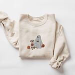 Sand crewneck sweatshirt laid flat on a white background, embroidered with a ghost lab mom holding a coffee cup and a jack-o'-lantern pail beside a tan lab in a ghost sheet with its own pumpkin pail
