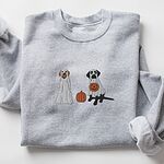 Sport Grey crewneck sweatshirt laid flat on a white background, embroidered with two Labrador ghosts: a light cream lab draped in a white sheet and a black lab in a sheet holding a jack-o'-lantern, with a pumpkin between them