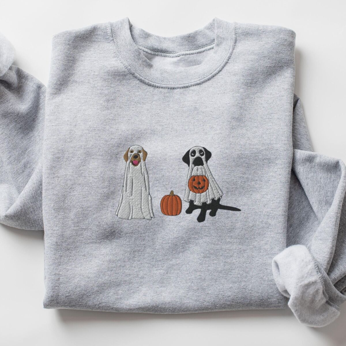 Labrador Ghosts Sweatshirt - Sport Grey Sport Grey crewneck sweatshirt laid flat on a white background, embroidered with two Labrador ghosts: a light cream lab draped in a white sheet and a black lab in a sheet holding a jack-o'-lantern, with a pumpkin between them