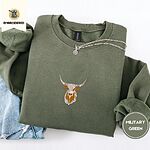 Military Green crewneck sweatshirt folded with light jeans and a silver chain necklace, embroidered with a longhorn steer head with cream and copper patches and long curved horns