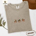 Khaki Comfort Colors T-shirt embroidered with three green-headed mallards in Santa hats, scarves and boots carrying a string of Christmas lights