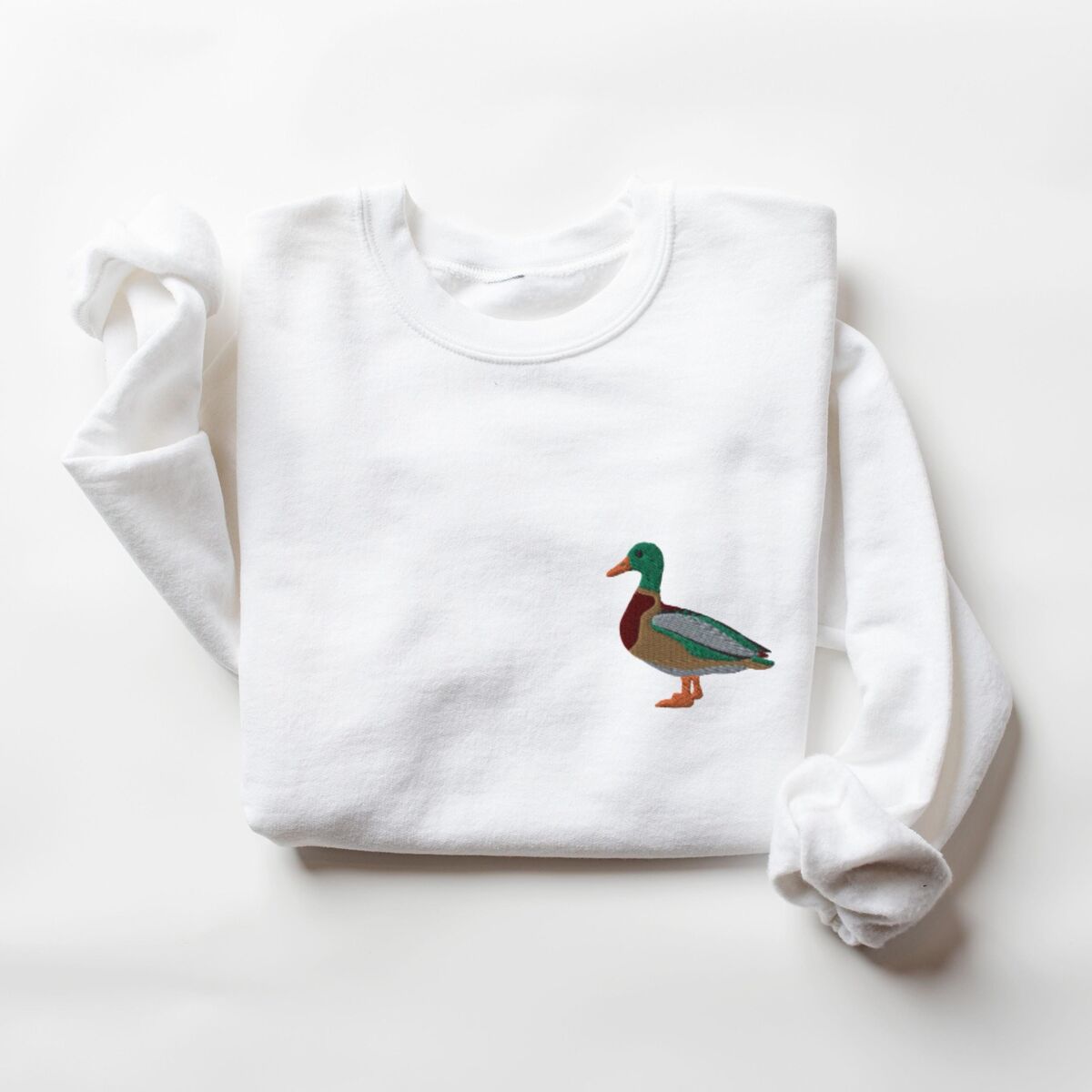 Mallard Crewneck - White White crewneck sweatshirt laid flat with a rolled cuff, embroidered with a standing drake mallard with a green head, orange bill, chestnut chest and grey wing on the left chest