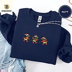 Navy crewneck sweatshirt folded with ripped jeans and a silver chain necklace, embroidered with three mallard ducks in Santa hats, knit scarves and orange boots carrying a string of Christmas lights