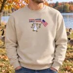 Man in a Sand Make Goose Great Again sweatshirt by a lake with Canada geese behind him