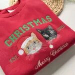 Folded red Merry Christmas pet sweatshirt with two cat portraits and EST 2025