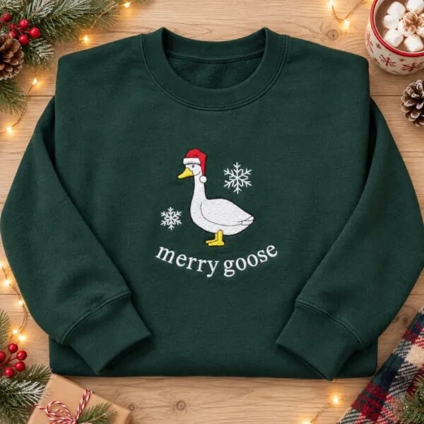 Christmas goose sweatshirt in Forest Green laid flat with pine sprigs, berries and a cup of cocoa