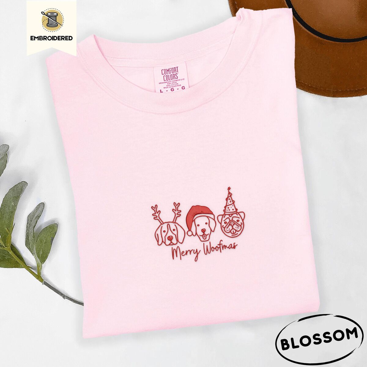Merry Woofmas Shirt – Blossom Blossom Comfort Colors T-shirt embroidered with three red line-art dog faces in Christmas hats above Merry Woofmas script