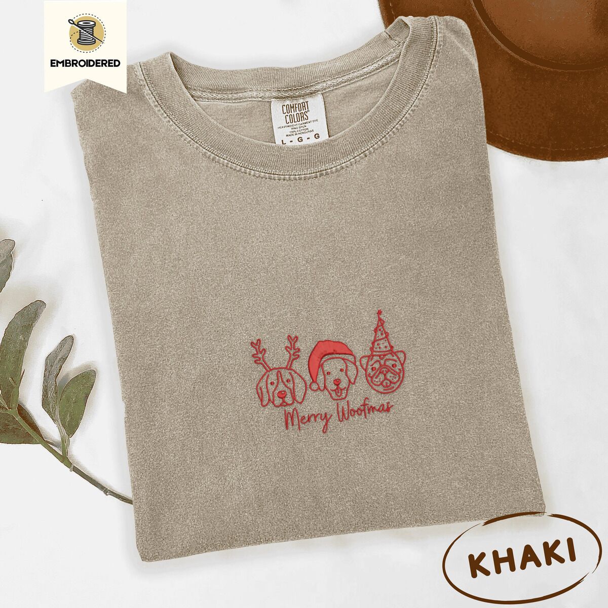 Merry Woofmas Shirt – Khaki Khaki Comfort Colors T-shirt embroidered with three red line-art dog faces in Christmas hats above Merry Woofmas script
