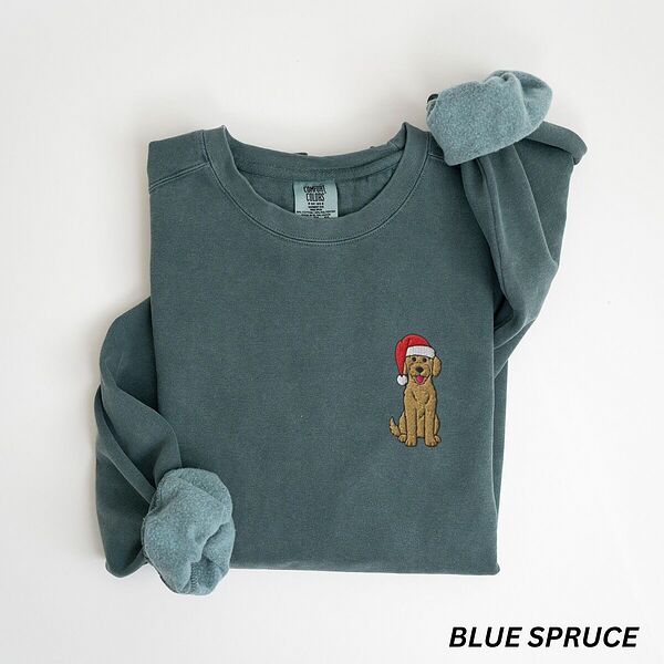 Blue Spruce crewneck sweatshirt laid flat, embroidered with a small goldendoodle sitting in a Santa hat on the left chest