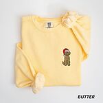 Butter crewneck sweatshirt laid flat, embroidered with a goldendoodle in a red Santa hat with a pink tongue