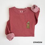 Crimson crewneck sweatshirt laid flat, embroidered with a small goldendoodle in a red Santa hat with its tongue out
