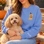 Miniature Poodle mom wearing the Heather Deep Royal Halloween sweatshirt with her Miniature Poodle on a fall porch