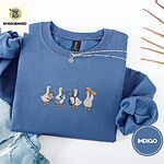 Indigo Blue crewneck sweatshirt folded with light jeans and dried twigs, embroidered with four white ducks holding a clipboard, a syringe, a stethoscope and a bandage