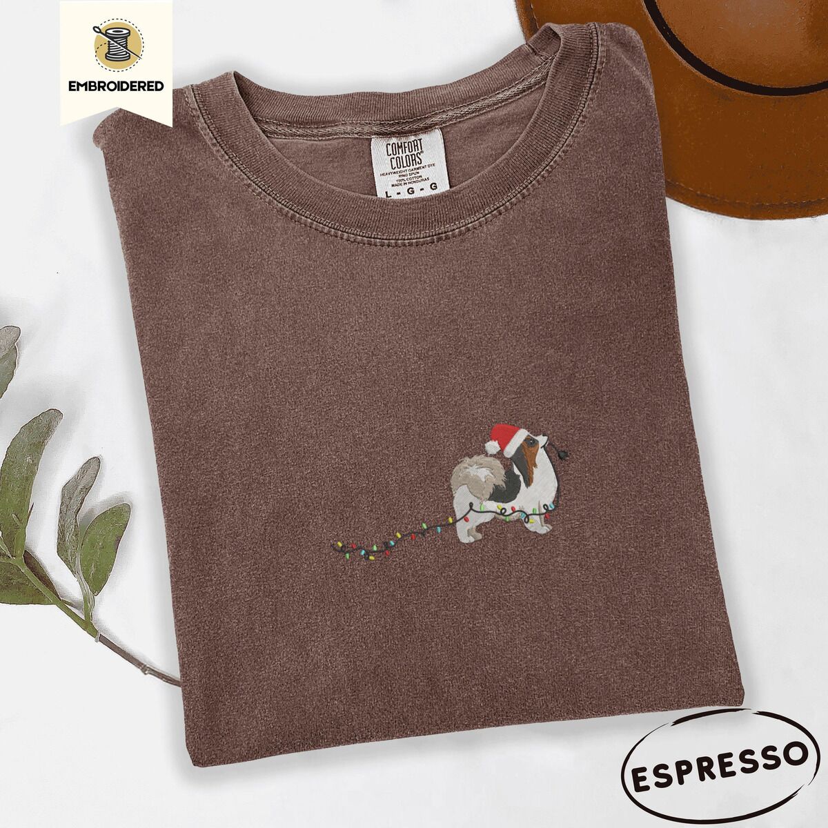 Papillon Christmas Lights Shirt – Espresso Espresso Comfort Colors T-shirt embroidered with a tricolor Papillon in a Santa hat holding the plug of a string of Christmas lights in its mouth
