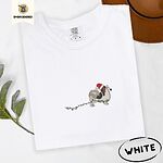 White Comfort Colors T-shirt embroidered with a tricolor Papillon in a Santa hat holding the plug of a string of Christmas lights in its mouth