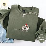 Military Green crewneck sweatshirt folded with light jeans and a silver chain necklace, embroidered with a tricolor Papillon in a Santa hat holding the plug of a string of Christmas lights in its mouth