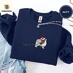 Navy crewneck sweatshirt folded with ripped jeans and a silver chain necklace, embroidered with a tricolor Papillon in a Santa hat holding the plug of a string of Christmas lights in its mouth