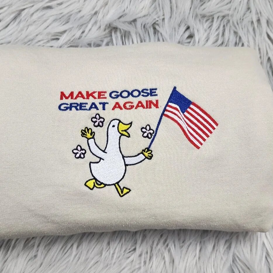 Patriotic Goose Embroidery – Close-up Close-up of the Make Goose Great Again embroidery, a marching goose with a U.S. flag and pink flowers
