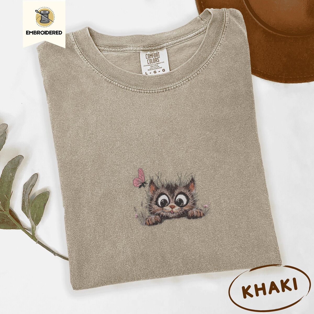 Peeking Cat Shirt – Khaki Khaki Comfort Colors T-shirt embroidered with a fluffy brown tabby kitten peeking over a ledge at a pink butterfly