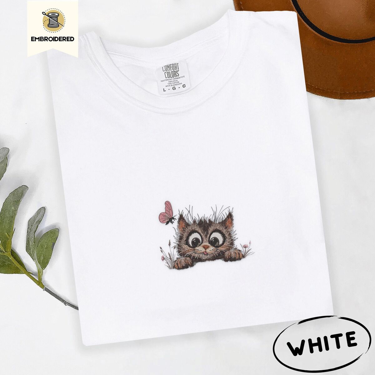 Peeking Cat Shirt – White White Comfort Colors T-shirt embroidered with a fluffy brown tabby kitten peeking over a ledge at a pink butterfly