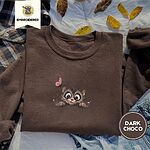 Dark Chocolate crewneck sweatshirt on a plaid flannel shirt with yellow autumn leaves and denim shorts, embroidered with a fluffy brown tabby kitten with big round eyes peeking over a ledge at a pink butterfly
