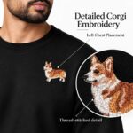 Close-up of the embroidered Pembroke Welsh corgi on the left chest of a black sweatshirt, with a zoomed view of the thread-stitched face