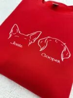Embroidered upright and floppy dog ears with the names Josie and Cooper on a red crewneck