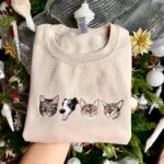 Sand sweatshirt with three embroidered tabby cat faces and a border collie face in a row