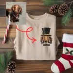 Sand sweatshirt with an embroidered dachshund portrait in a snowman top hat and the name RAMONA, made from the dog photo shown beside it