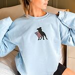 Woman in a Light Blue crewneck sweatshirt with a black pit bull holding a USA flag centered on the chest