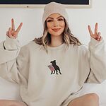 Woman in a beanie making peace signs in a sand crewneck sweatshirt with a pit bull silhouette and flag