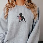 Woman in a sport grey crewneck sweatshirt with a black pit bull holding an American flag on the chest