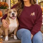 Woman wearing the maroon embroidered pitbull shirt on porch steps with her fawn and white pit bull