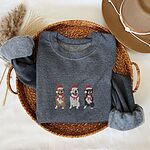 Dark Heather crewneck sweatshirt folded in a woven basket, embroidered with three sitting pitbulls, fawn, white and black, in red Santa hats and red scarves